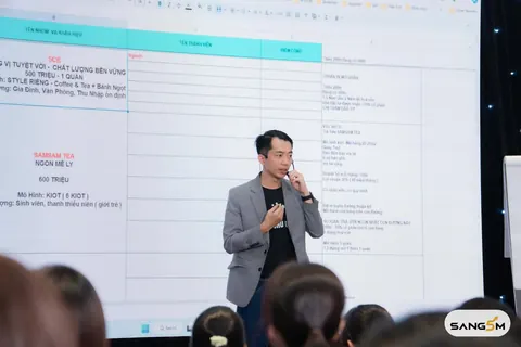 Hồ Đăng Sang cầm mic giảng trước màn hình lớn, học viên ngồi kín phía dưới