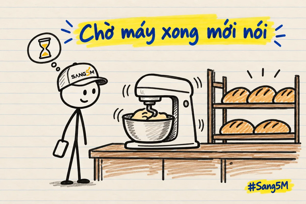 Tiệm bánh có máy trộn bột đang chạy rung, người đội nón SANG5M đứng chờ bên cạnh, tay cầm điện thoại hạ xuống.